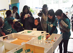 「おおつち学園」の模型を見る参加者たち