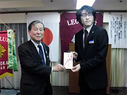 鎌田会長(右)から守谷常務理事に贈呈