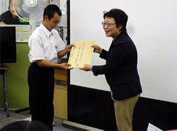 新沼光晟リーダー長(左)に「手紙と写真」(上の右の写真)を渡す藤原綾子事務局長