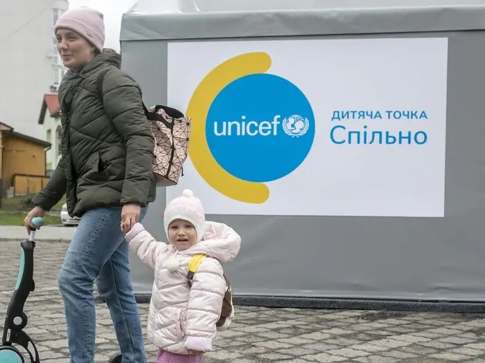 リヴィウにある、国内避難民のためのユニセフの施設の前を通る親子（ウクライナ、3月31日撮影）